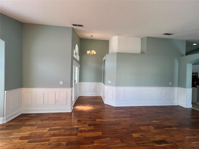 empty room with an inviting chandelier, visible vents, and wood finished floors