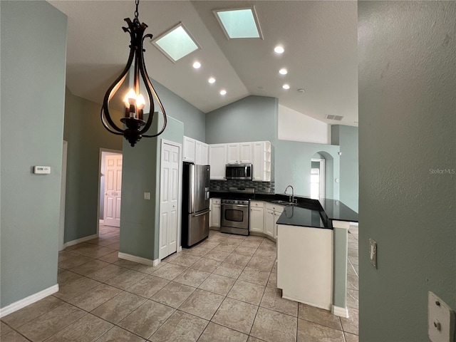 kitchen with arched walkways, dark countertops, a peninsula, stainless steel appliances, and a sink