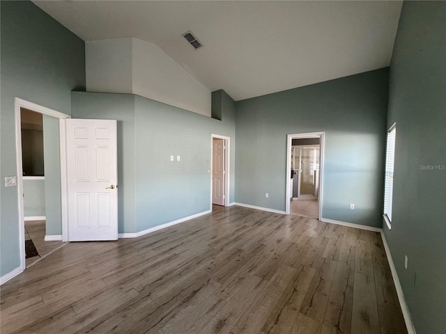 unfurnished room featuring high vaulted ceiling, visible vents, baseboards, and wood finished floors