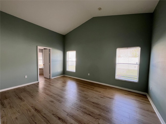 spare room with lofted ceiling, baseboards, and wood finished floors