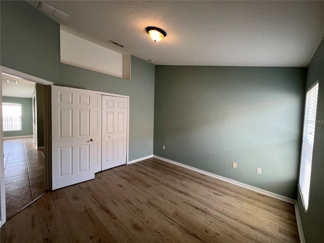 unfurnished bedroom featuring baseboards, visible vents, wood finished floors, a textured ceiling, and a closet