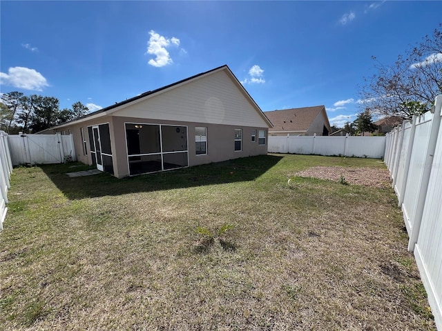 rear view of property featuring a lawn, a fenced backyard, and a sunroom