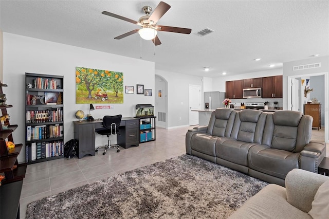 living area with arched walkways, light tile patterned floors, a textured ceiling, and visible vents