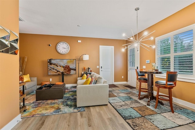 living area featuring baseboards, wood finished floors, visible vents, and an inviting chandelier