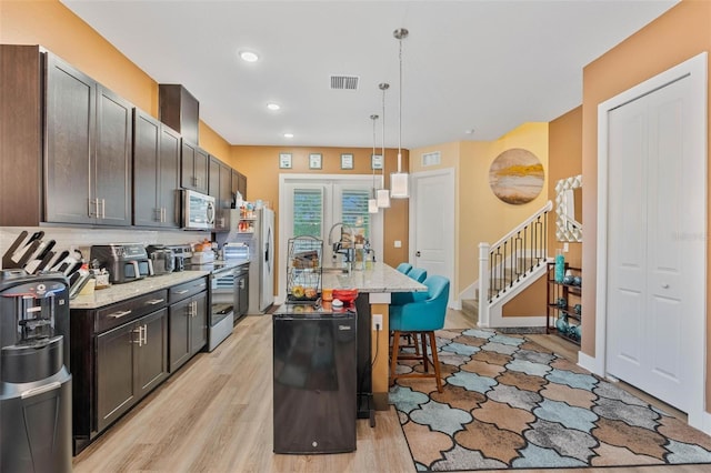 kitchen featuring pendant lighting, a breakfast bar area, stainless steel appliances, visible vents, and light wood-style floors