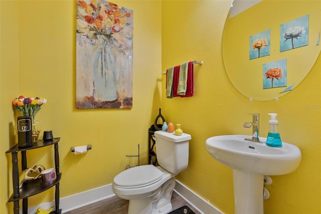 bathroom with wood finished floors, toilet, and baseboards