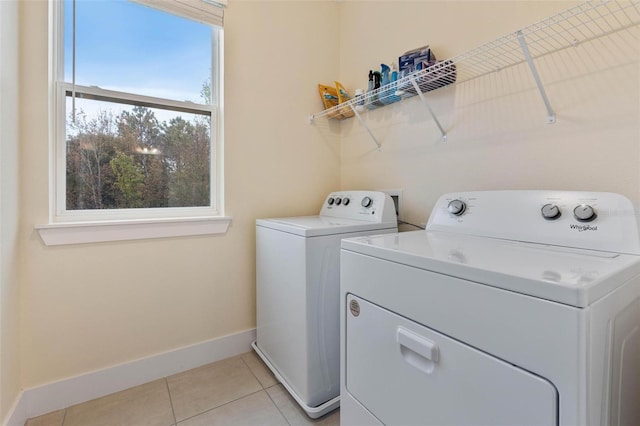 clothes washing area with light tile patterned floors, laundry area, independent washer and dryer, and baseboards