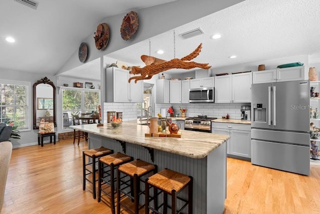 kitchen featuring lofted ceiling, tasteful backsplash, a breakfast bar area, and stainless steel appliances