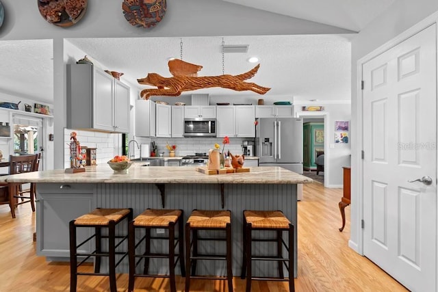 kitchen with visible vents, decorative backsplash, a peninsula, stainless steel appliances, and a sink