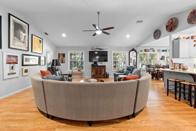 living room with baseboards, visible vents, vaulted ceiling, and light wood finished floors