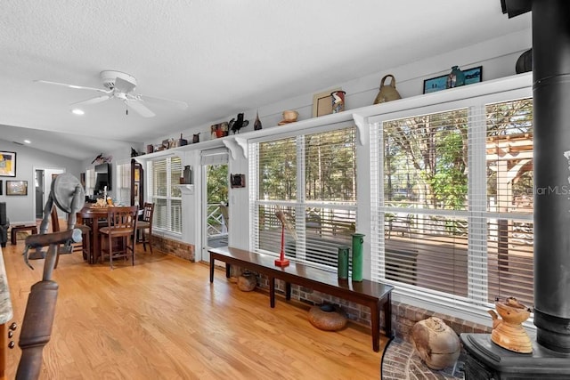 sunroom with a wood stove, ceiling fan, and lofted ceiling