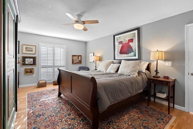 bedroom featuring baseboards, ceiling fan, light wood-style flooring, and a textured ceiling