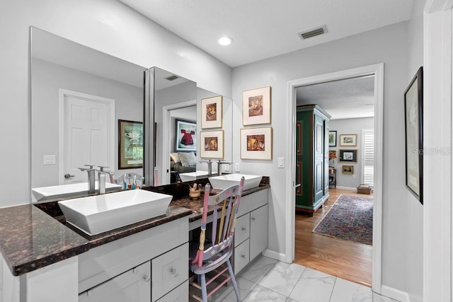 bathroom with double vanity, baseboards, visible vents, marble finish floor, and a sink