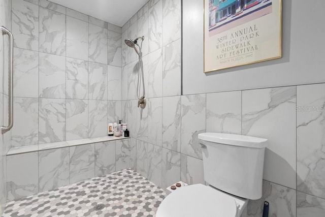 bathroom featuring a tile shower, toilet, and tile walls