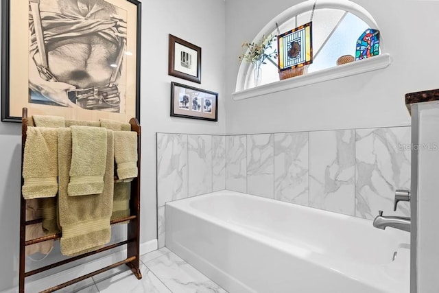 full bathroom with marble finish floor and a tub