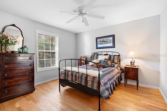 bedroom with a ceiling fan, baseboards, and light wood finished floors