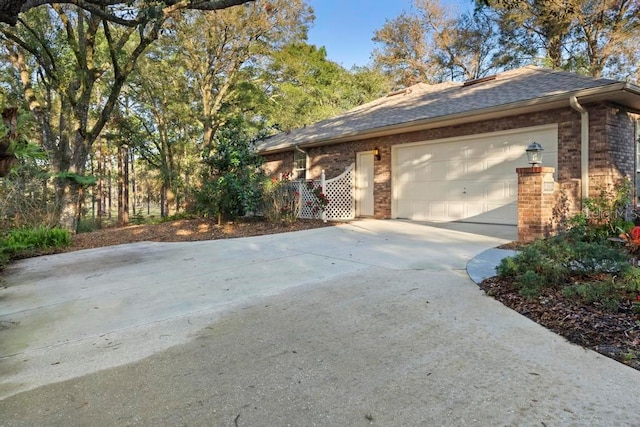 ranch-style house with brick siding, driveway, an attached garage, and roof with shingles