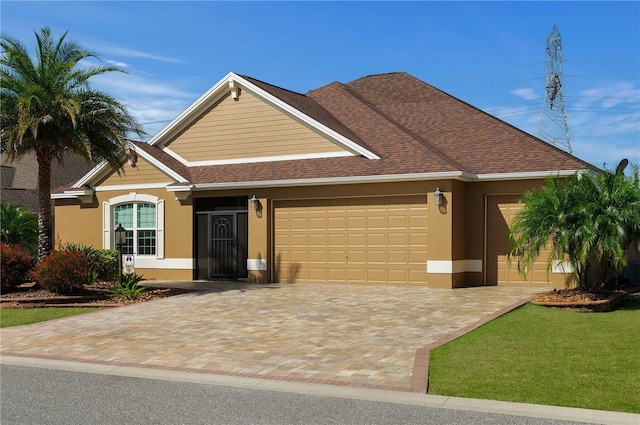 view of front of home featuring decorative driveway, an attached garage, roof with shingles, and stucco siding