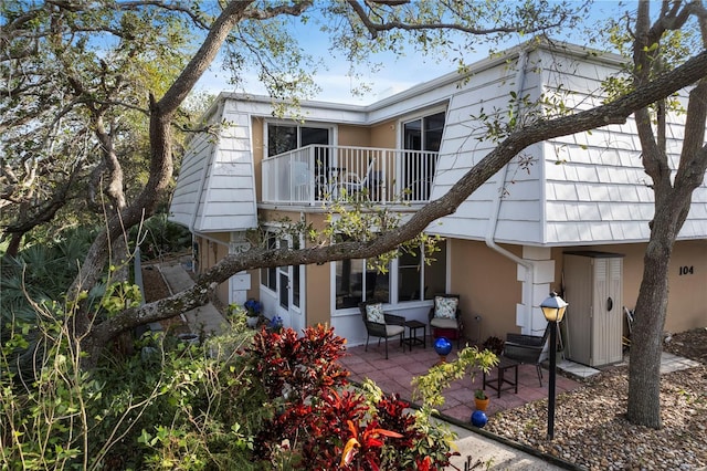 rear view of property featuring a patio area, a balcony, and stucco siding