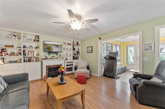 living area featuring light wood-type flooring, a brick fireplace, and ceiling fan