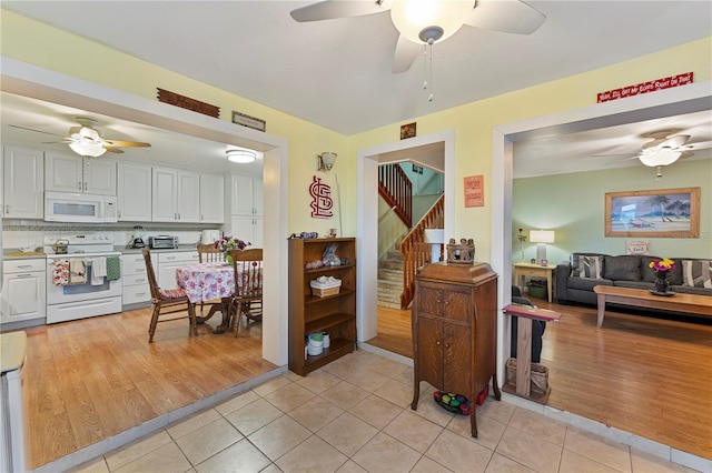 interior space featuring light tile patterned floors, white appliances, open floor plan, and white cabinetry