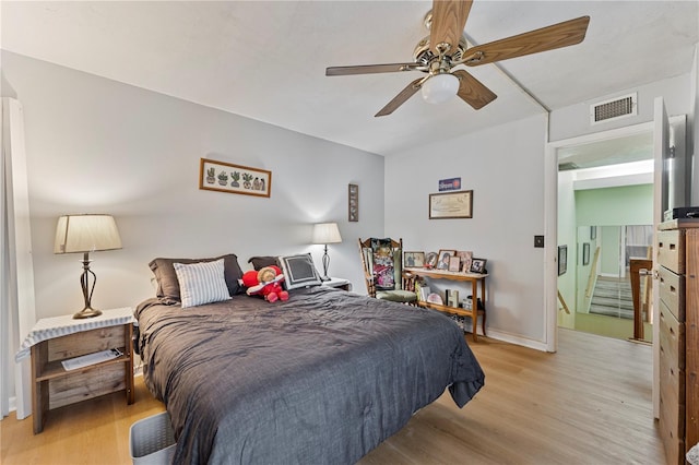 bedroom featuring light wood finished floors, baseboards, visible vents, and a ceiling fan