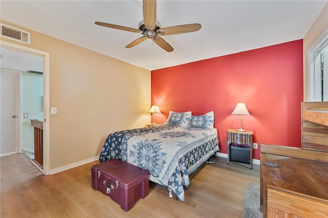 bedroom featuring baseboards, visible vents, ceiling fan, and wood finished floors