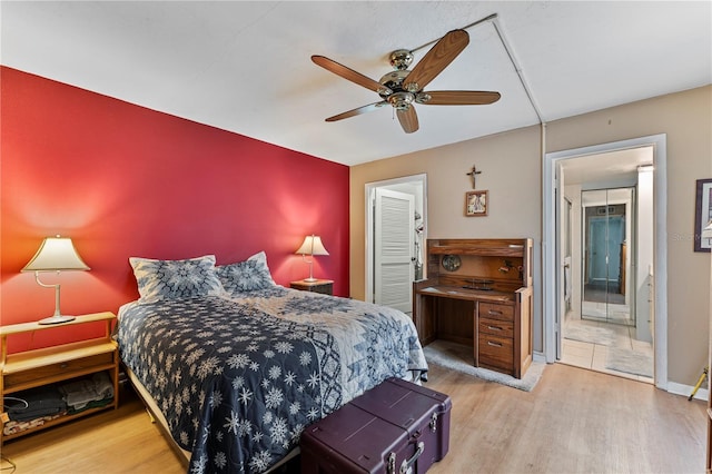 bedroom with ensuite bathroom, wood finished floors, a ceiling fan, baseboards, and a closet