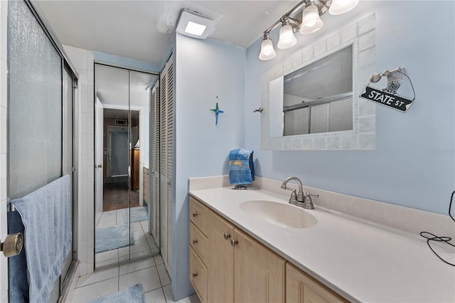 bathroom with a shower with shower door, tile patterned floors, a closet, and vanity