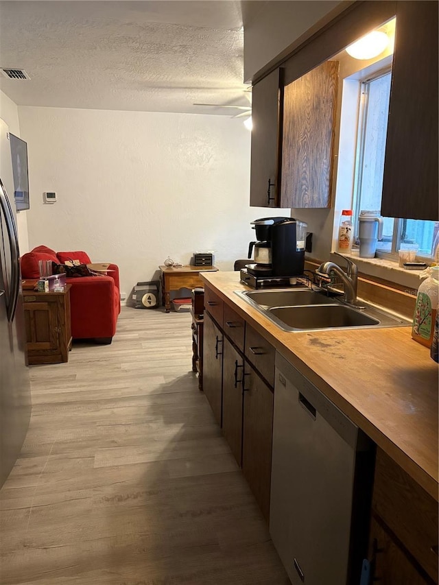 kitchen featuring stainless steel appliances, dark brown cabinetry, a textured ceiling, light hardwood / wood-style floors, and sink