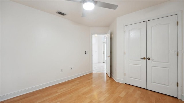 unfurnished bedroom with ceiling fan, light wood-type flooring, and a closet