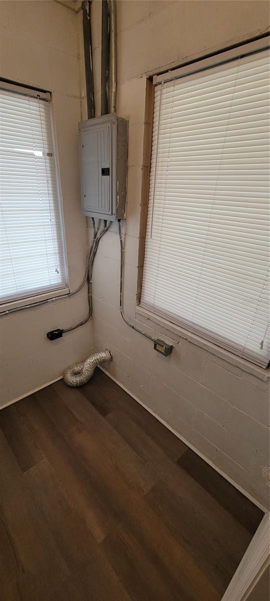 interior space with wood finished floors, electric panel, and concrete block wall