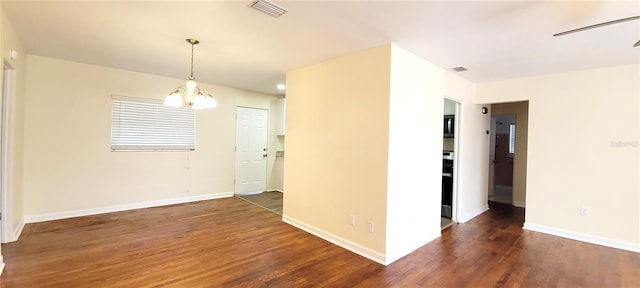 unfurnished room with dark wood-type flooring, a chandelier, visible vents, and baseboards