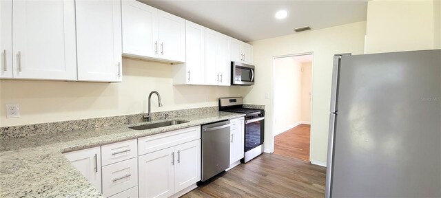 kitchen featuring visible vents, white cabinets, light stone countertops, stainless steel appliances, and a sink