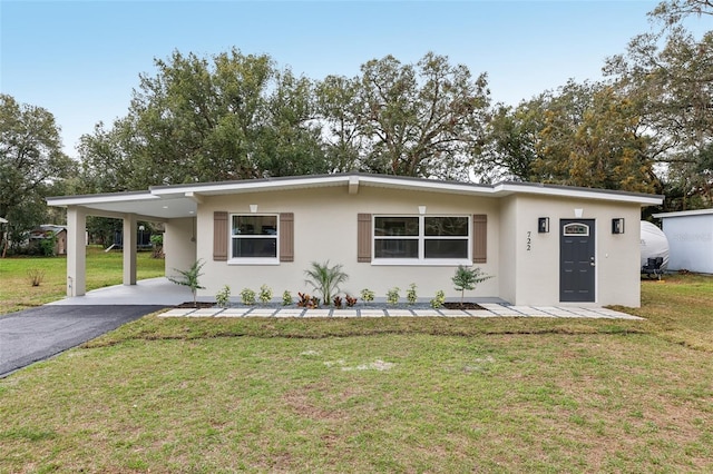 view of front facade with a carport, a front yard, stucco siding, and aphalt driveway