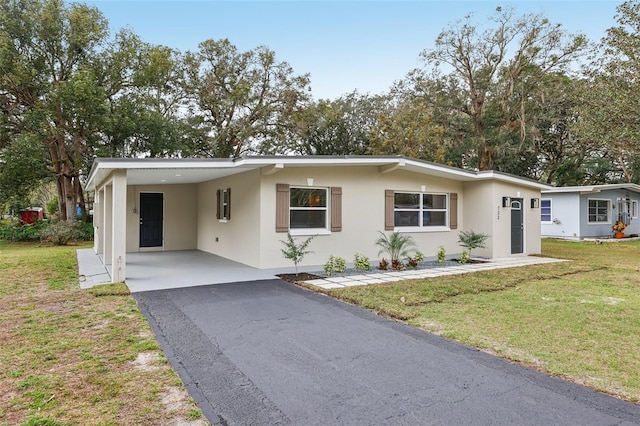 view of front of property featuring a carport, aphalt driveway, a front lawn, and stucco siding