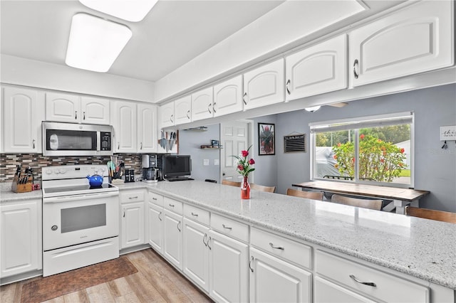 445 Virginia Ave, Saint Cloud, FL 34769 - kitchen featuring stainless steel microwave, white electric range, tasteful backsplash, white cabinets, and light wood-type flooring