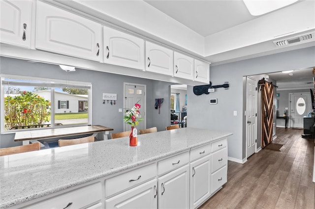 445 Virginia Ave, Saint Cloud, FL 34769 - kitchen featuring light stone counters, wood finished floors, white cabinetry, and baseboards