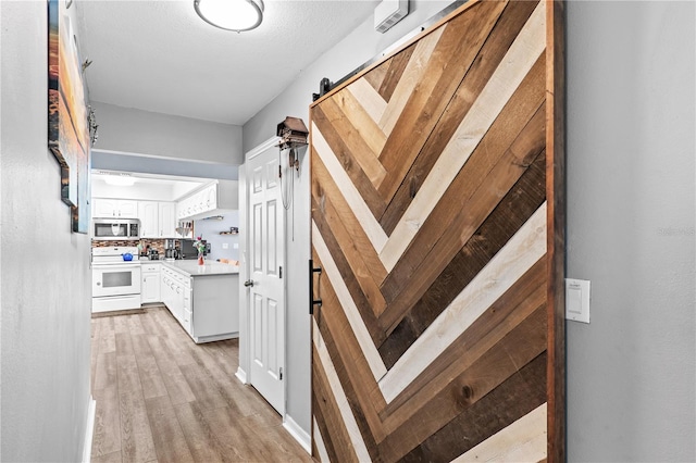 445 Virginia Ave, Saint Cloud, FL 34769 - corridor featuring light wood-style flooring and a barn door