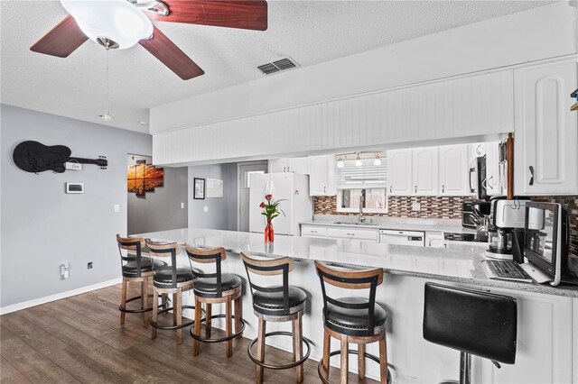 445 Virginia Ave, Saint Cloud, FL 34769 - kitchen featuring white appliances, dark wood-style flooring, decorative backsplash, white cabinetry, and a peninsula