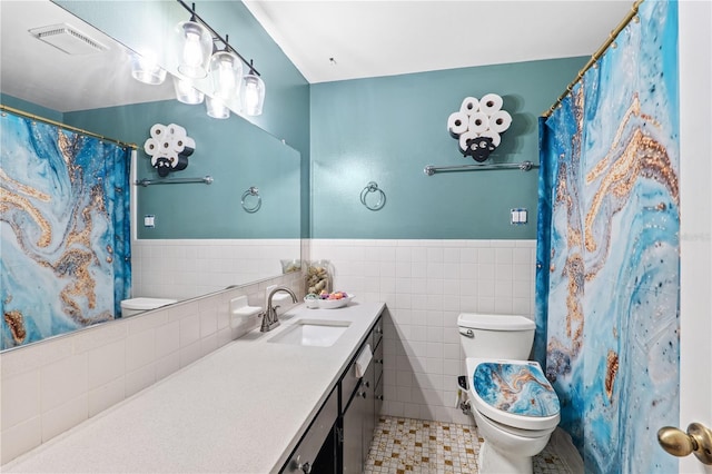 445 Virginia Ave, Saint Cloud, FL 34769 - bathroom featuring toilet, vanity, a wainscoted wall, tile walls, and tile patterned flooring