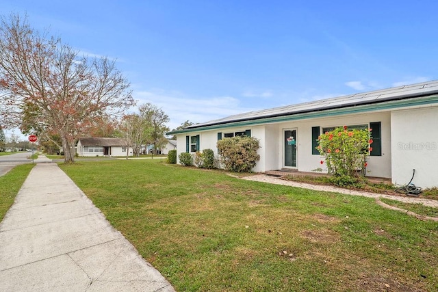 445 Virginia Ave, Saint Cloud, FL 34769 - single story home with stucco siding, a front yard, and roof mounted solar panels