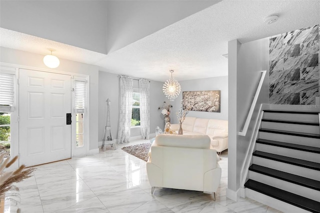 entrance foyer featuring marble finish floor, stairway, baseboards, and a textured ceiling