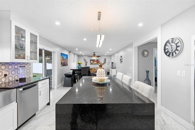 kitchen featuring dark stone counters, glass insert cabinets, marble finish floor, white cabinetry, and stainless steel dishwasher