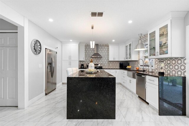 kitchen with a center island, stainless steel appliances, visible vents, glass insert cabinets, and wall chimney range hood