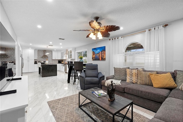 living room with marble finish floor, a textured ceiling, visible vents, and a ceiling fan