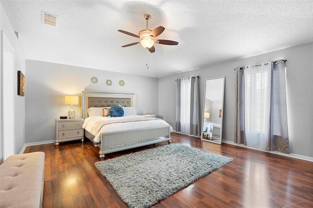 bedroom with baseboards, a textured ceiling, visible vents, and dark wood-style flooring