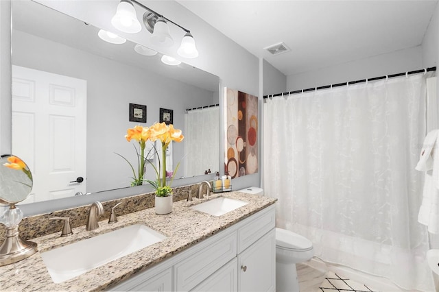 bathroom featuring double vanity, visible vents, toilet, and a sink