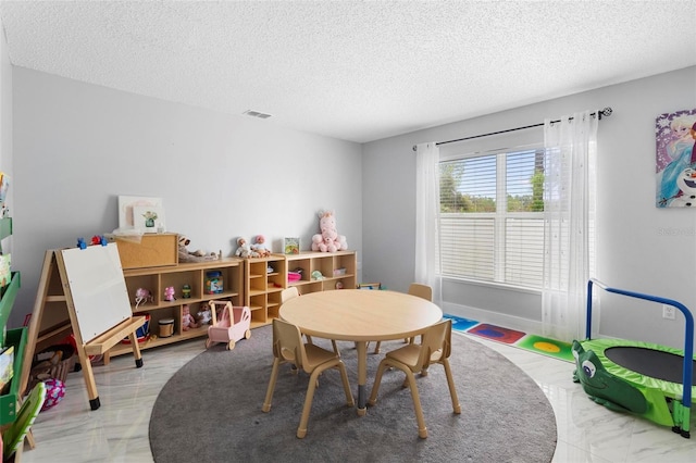 rec room with visible vents, a textured ceiling, and baseboards