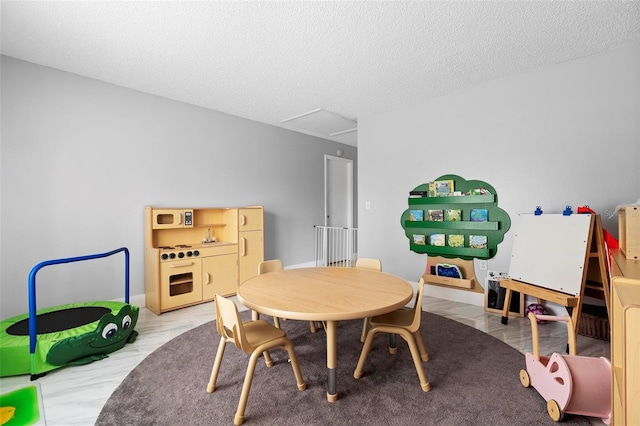 game room featuring light wood-type flooring, a textured ceiling, and baseboards